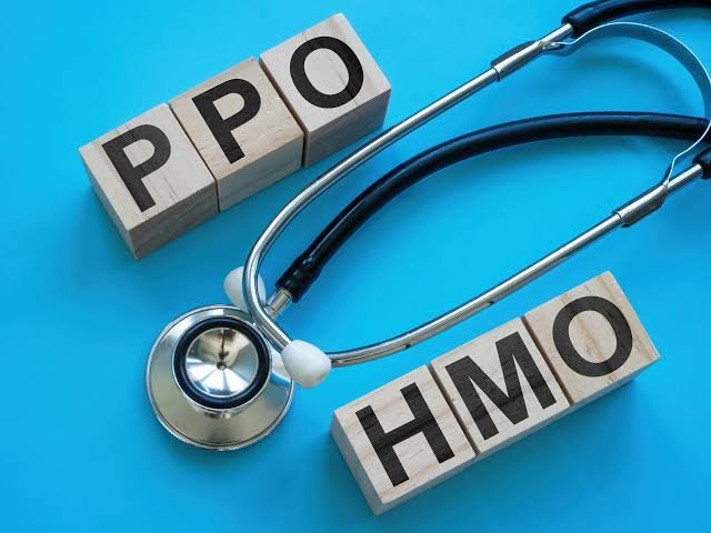 Wooden blocks spelling HMO and PPO next to a stethoscope