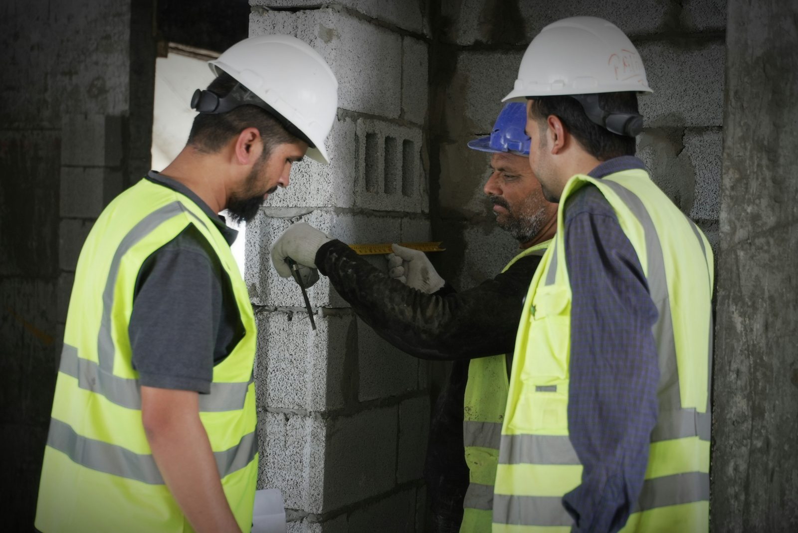 Two construction workers measuring a block wall on site