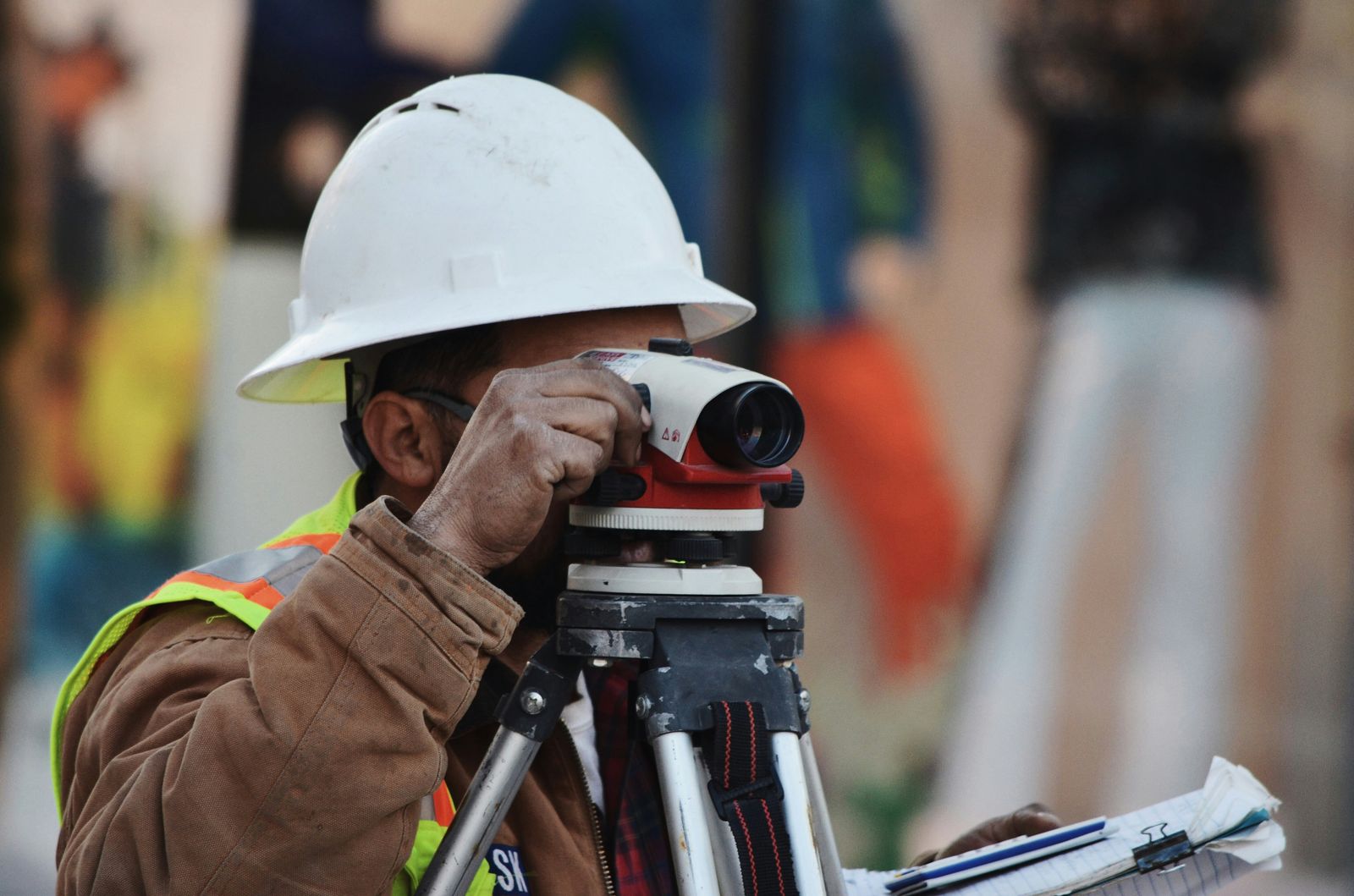 Worker checking a survey level on a job site, planning ahead like a new owner-operator