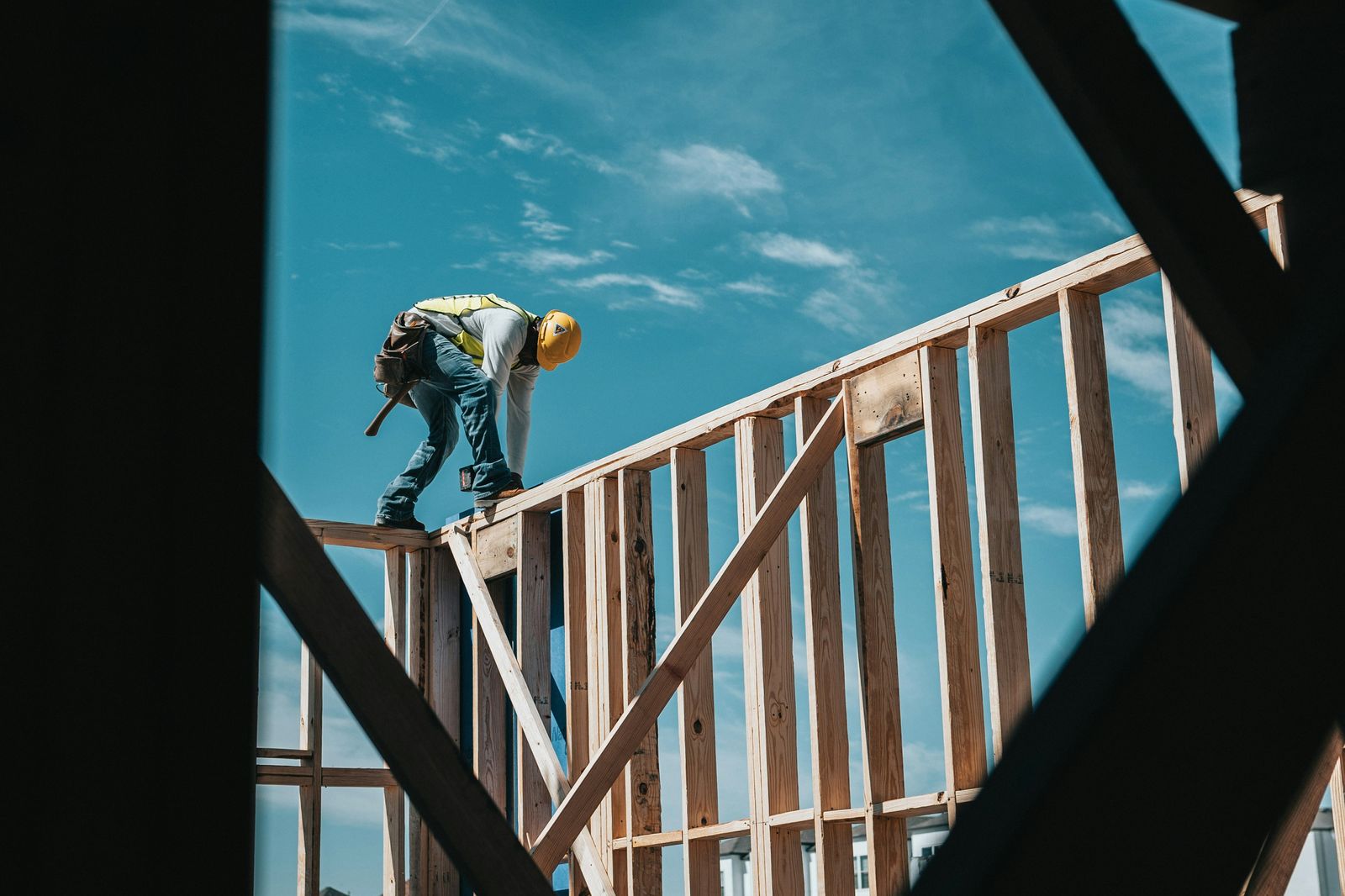 Construction crew member framing a building against a blue sky