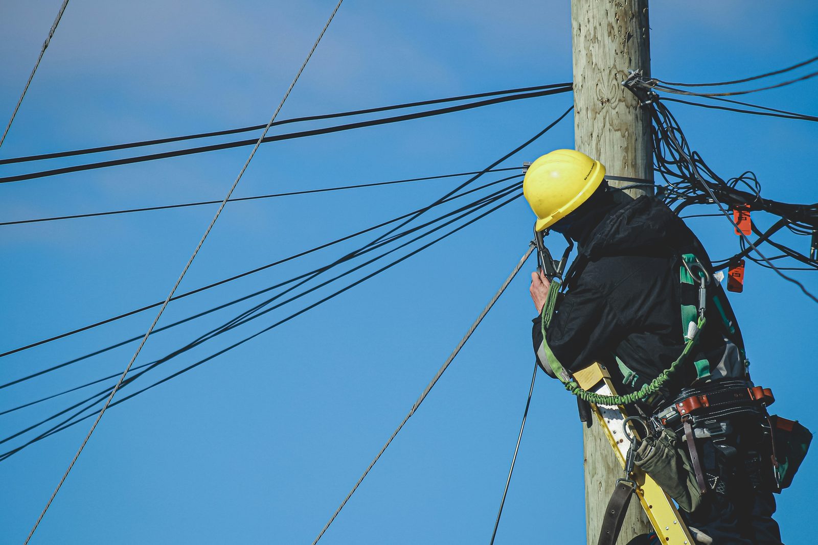 Electrical lineman working on a utility pole, representing trade contractor health benefits