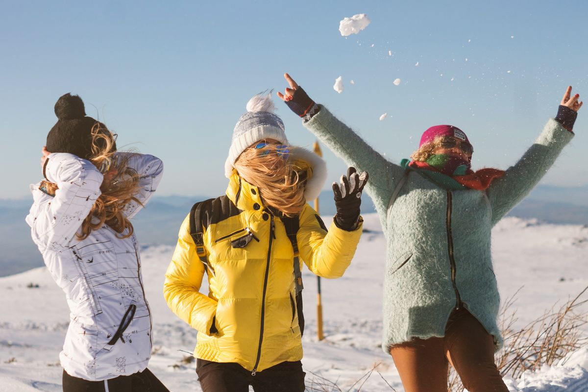 Young adult friends having fun throwing snow on a mountain