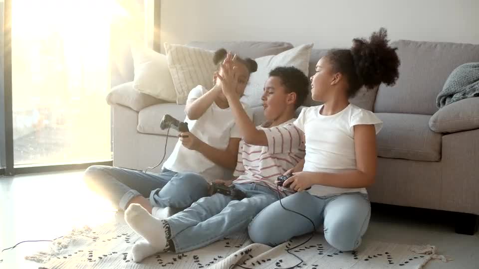 Siblings laughing together on the living room couch