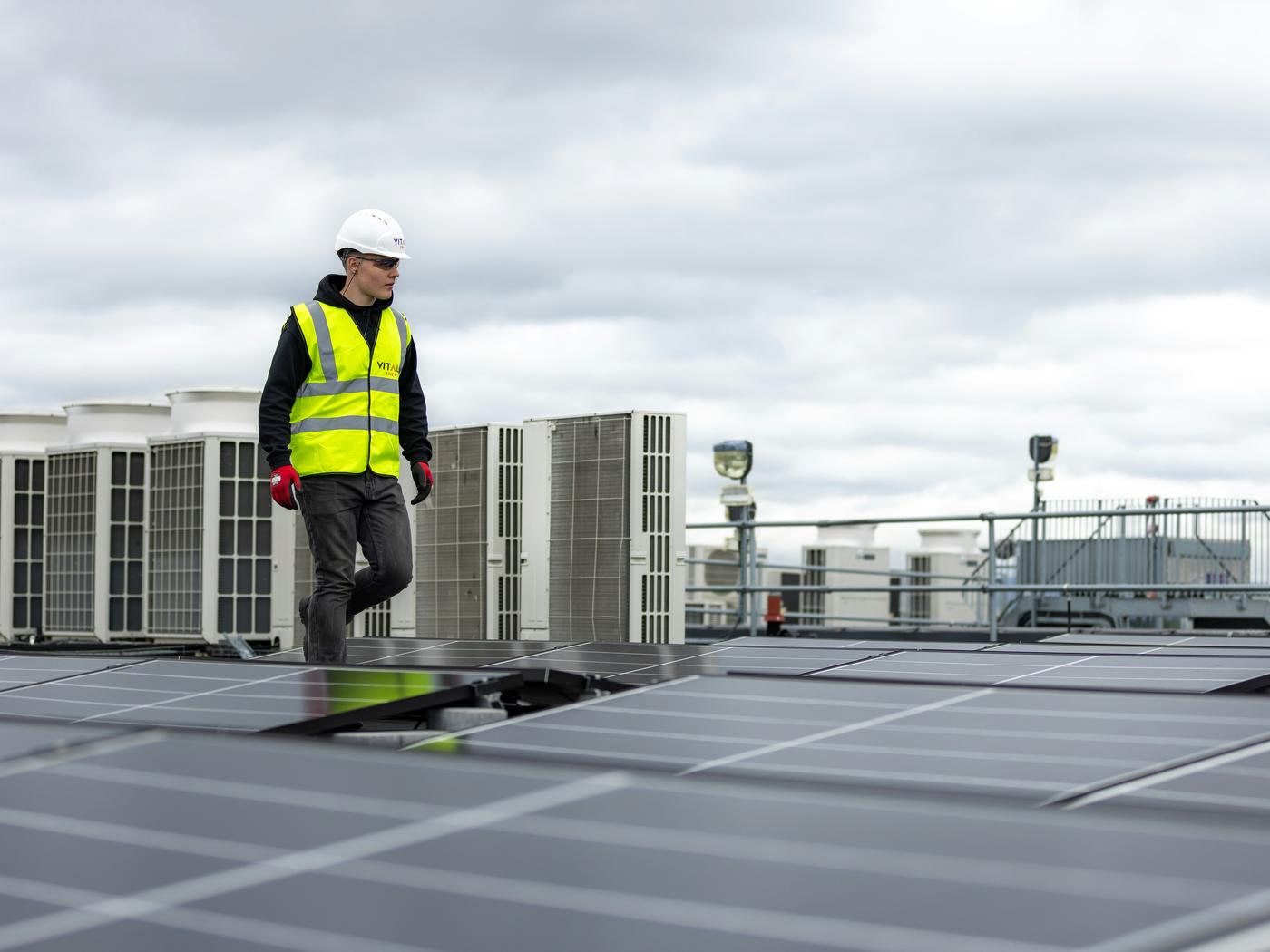 HVAC technician on a rooftop between condenser units, covered by company group health insurance