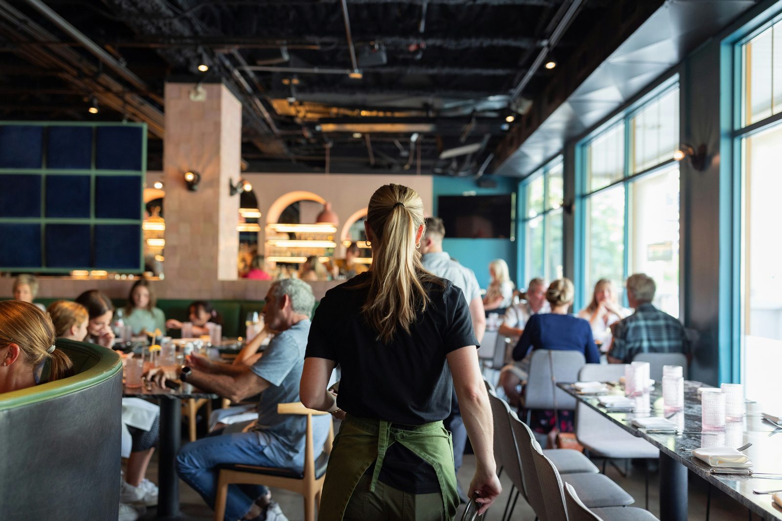 Server crossing a busy restaurant dining room in South Florida