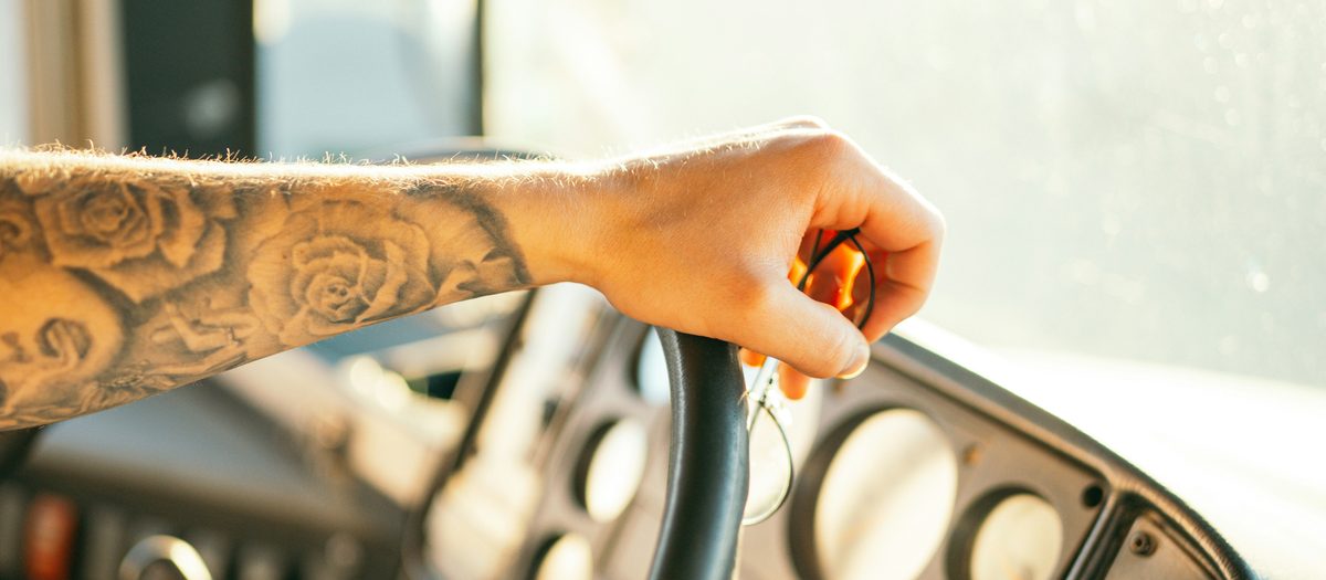Truck driver's hands on the steering wheel at sunrise, illustrating nationwide PPO health insurance coverage for over-the-road drivers